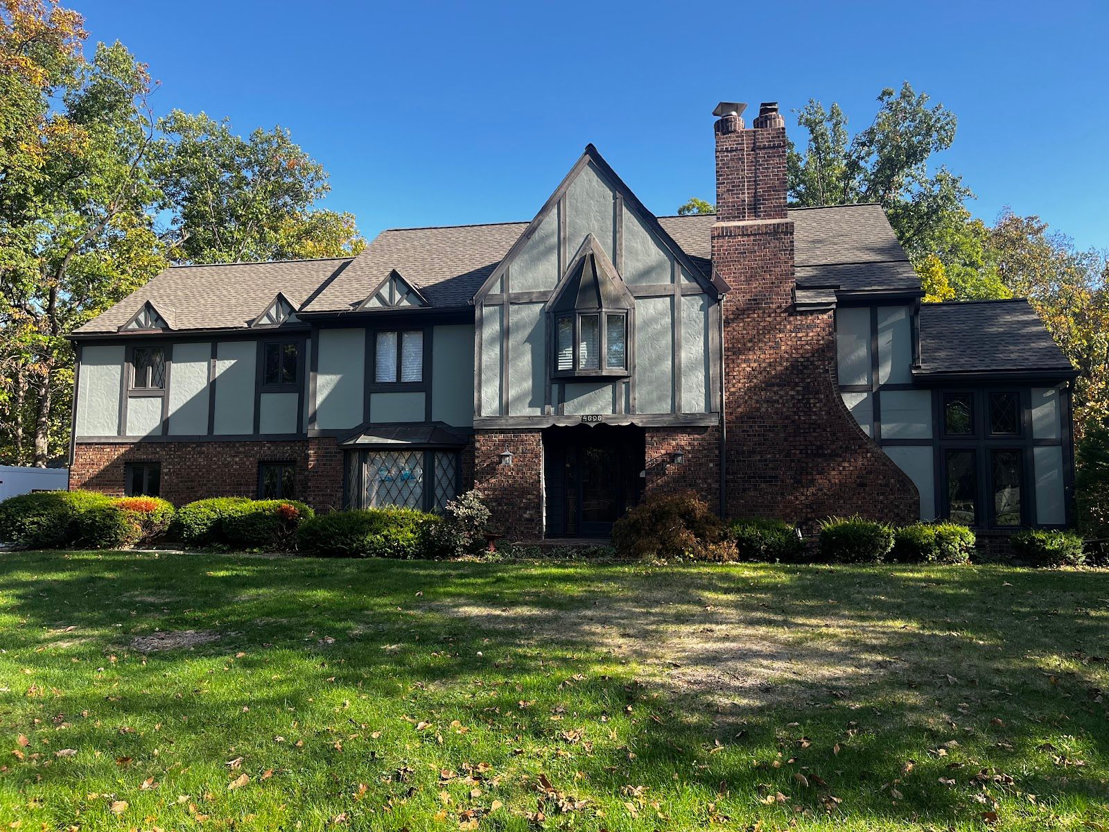 Before - Tudor-style home in Schererville, IN with faded green siding panels and dark trim